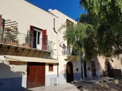 a white building with a wooden door and a tree at Boutique House Montevergini in Palermo