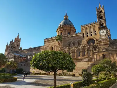 a large building with a clock tower and a tree at Boutique House Montevergini in Palermo