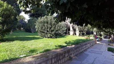 a park with a stone wall and a grass field at se vi pare in Palermo