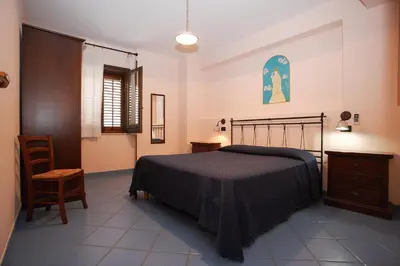 a bedroom with a bed and a chair at La Chiusa Case Vacanze in Castellammare del Golfo