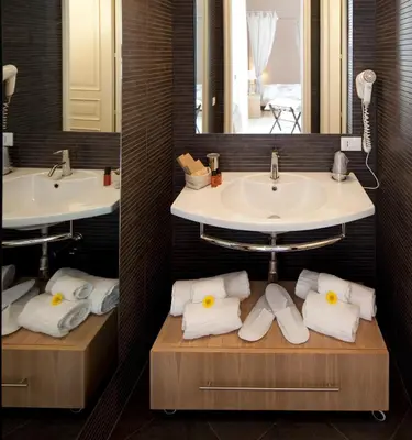 a bathroom with two sinks and two mirrors and towels at Palazzo Brunaccini Boutique Hotel in Palermo