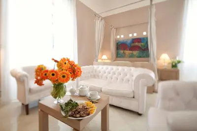 a living room with a white couch and flowers on a table at Palazzo Brunaccini Boutique Hotel in Palermo