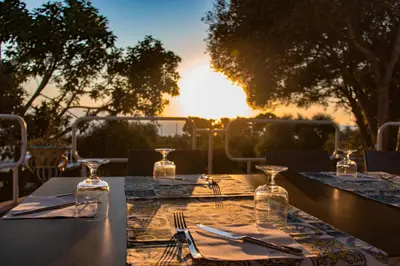 a table set for dinner with the sunset in the background at CDSHotels Terrasini - Città del Mare in Terrasini