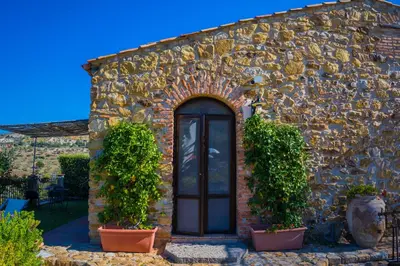 a stone building with a door and two plants at Poggio Pozzetti in Lascari