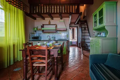 a kitchen with green cabinets and a table and chairs at Poggio Pozzetti in Lascari
