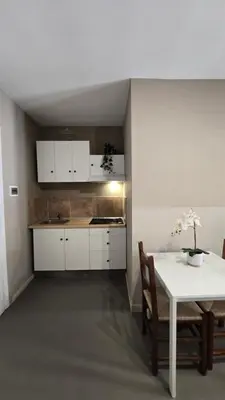a kitchen with white cabinets and a table with chairs at House Orlando in Sferracavallo