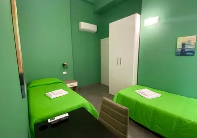 a green room with two beds and a table at Oasi del Turista in Palermo