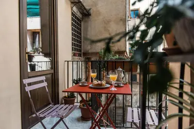 a table on a balcony with two glasses of wine at B&B Malvasia in Palermo