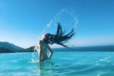 a woman in the water with her hair in the water at Hotel Antica Cascina Del Golfo in Scopello