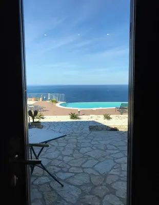 an open door to a view of a beach at Hotel Antica Cascina Del Golfo in Scopello