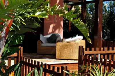 a patio with a wicker chair on a wooden deck at Villa Le Meraviglie in San Vito lo Capo