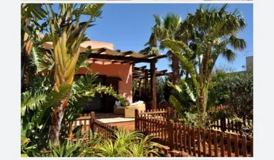 a house with a wooden fence and palm trees at Villa Le Meraviglie in San Vito lo Capo