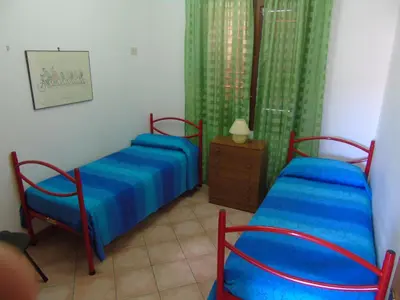 a bedroom with two beds and a dresser and curtains at Appartamento Marconi 15 in San Vito lo Capo
