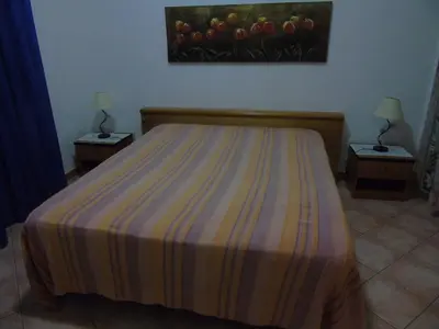 a bedroom with a bed with a striped bedspread and two tables at Appartamento Marconi 15 in San Vito lo Capo
