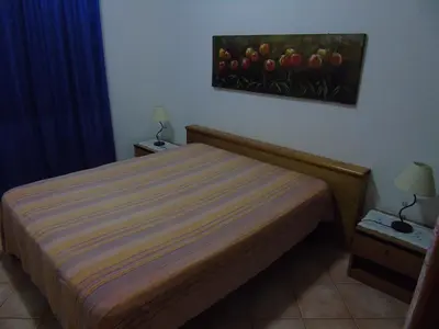 a bedroom with a bed with a painting on the wall at Appartamento Marconi 15 in San Vito lo Capo