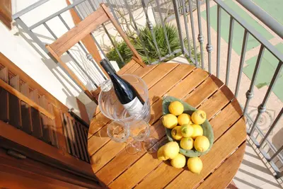 a wooden table with a bowl of fruit and a bottle of wine at sicily home casa vacanze con piscina in San Vito lo Capo