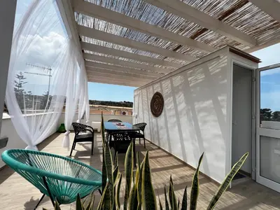 a patio with a table and chairs on a balcony at sicily home casa vacanze con piscina in San Vito lo Capo