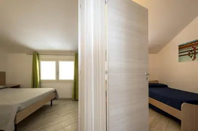 a bedroom with a bed and a door to a room at Borgo Aranci - Villetta a schiera Lavanda - A8 in Castellammare del Golfo