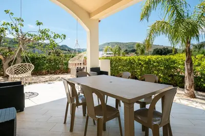 a wooden table and chairs on a patio at Borgo Aranci - Villetta a schiera Lavanda - A8 in Castellammare del Golfo