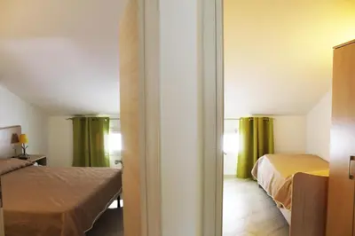 a bedroom with two beds and green curtains at Borgo Aranci - Villetta Peonia B3 - Castellammare del Golfo in Castellammare del Golfo