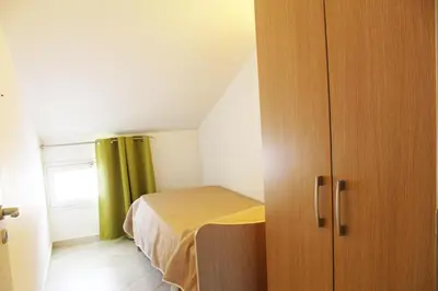 a small bedroom with a bed and a wooden cabinet at Borgo Aranci - Villetta Peonia B3 - Castellammare del Golfo in Castellammare del Golfo
