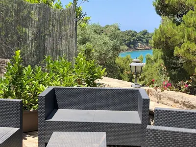 a wicker bench with a view of the water at Villa Mariza in Scopello