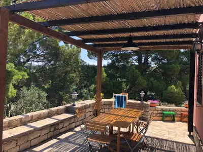 a wooden pergola with a wooden table and chairs on a patio at Villa Mariza in Scopello