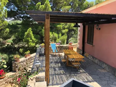 a patio with a table and chairs under a wooden pergola at Villa Mariza in Scopello