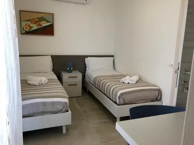 a bedroom with two beds and a blue chair at Villa Vo' Scurá in Alcamo Marina