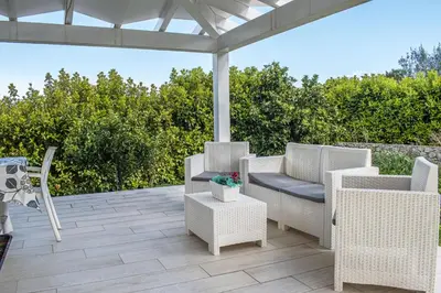 a patio with wicker chairs and a pergola at Borgo Aranci - Villa Tulipano in Castellammare del Golfo