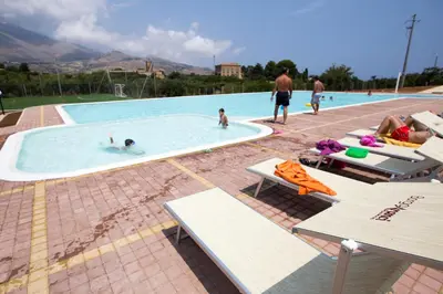 a group of people swimming in a swimming pool at Borgo Aranci - Villa Tulipano in Castellammare del Golfo