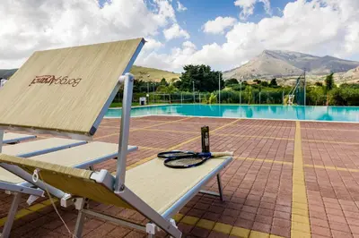 a bench with a laptop sitting on it next to a pool at Borgo Aranci - Villa Tulipano in Castellammare del Golfo