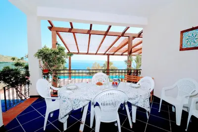a dining room with a table and white chairs at Villa Calamazzo in Scopello