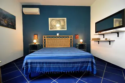 a bedroom with a bed with a blue wall at Villa Calamazzo in Scopello
