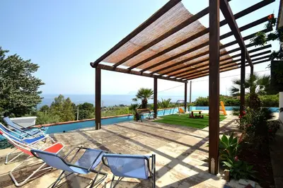 a group of chairs on a patio next to a swimming pool at Villa Calamazzo in Scopello