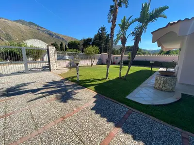 a walkway leading to a yard with palm trees at Villa Paloma in Castellammare del Golfo