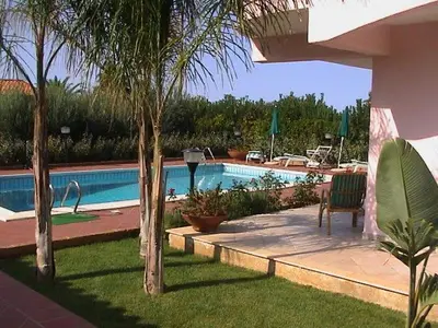 a swimming pool with palm trees in a yard at Villa Paloma in Castellammare del Golfo