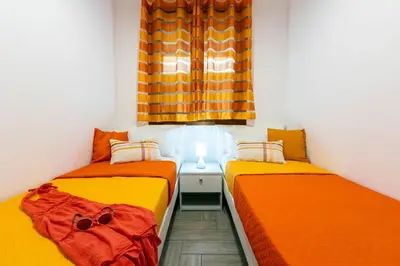 two beds in a small room with orange sheets at Il Faro Casa Vacanze Design Privacy Comfort e Posto Auto in San Vito lo Capo