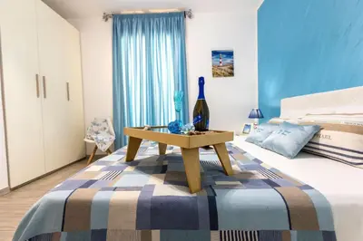 a bedroom with a bed with a table with a bottle of wine at Il Faro Casa Vacanze Design Privacy Comfort e Posto Auto in San Vito lo Capo