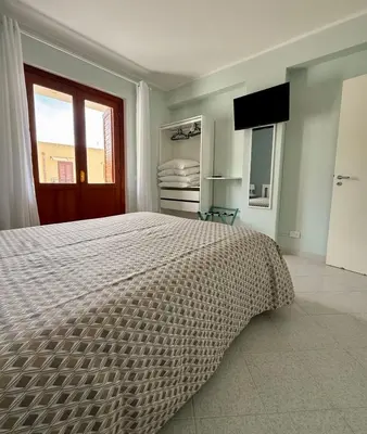 a bedroom with a large bed and a window at Yucca Apartment in San Vito lo Capo