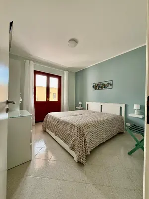a bedroom with a bed and a red door at Yucca Apartment in San Vito lo Capo