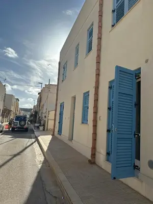 a building with a blue door on the side of a street at appartamento residence via giardini Acquamarina in San Vito lo Capo