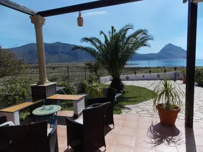 a patio with a table and chairs and a view of the ocean at Villa vista MARE a MÀKARI in San Vito lo Capo
