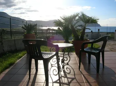 two chairs and a table on a patio with plants at Villa vista MARE a MÀKARI in San Vito lo Capo