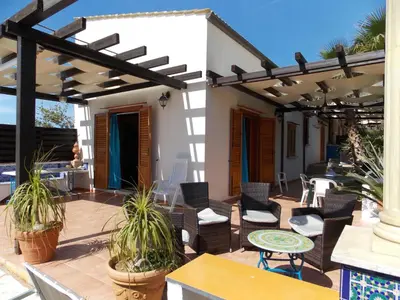 a patio with chairs and tables and a pergola at Villa vista MARE a MÀKARI in San Vito lo Capo