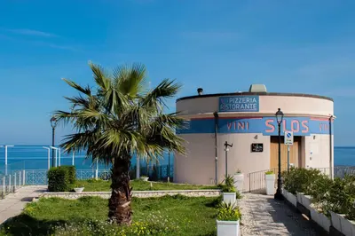 a building with a palm tree in front of it at Borgo Aranci - Villetta a Schiera A1 in Castellammare del Golfo