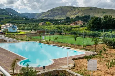 a pool with a tennis court and mountains in the background at Borgo Aranci - Villetta a Schiera A1 in Castellammare del Golfo