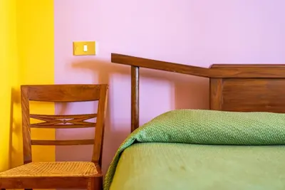 a bedroom with a bed and a chair at Stenopus Greco Casa per AFFITTI TURISTICI in Santa Flavia