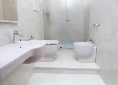 a white bathroom with a toilet and a sink at Hotel Egitarso Sul Mare in San Vito lo Capo