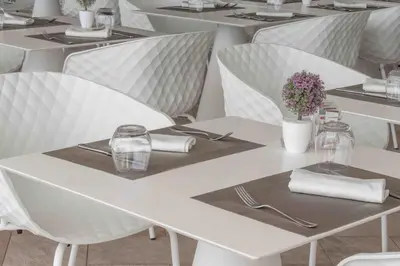 a row of white tables and chairs in a restaurant at Hotel Egitarso Sul Mare in San Vito lo Capo